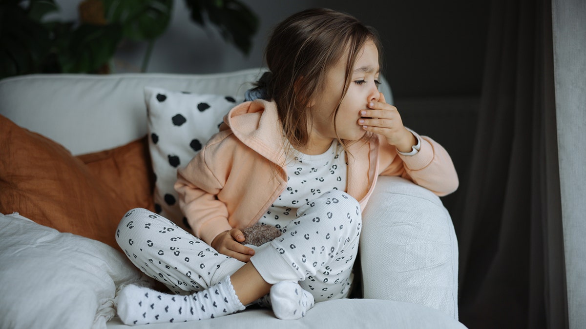 The girl covers her mouth as she tosses